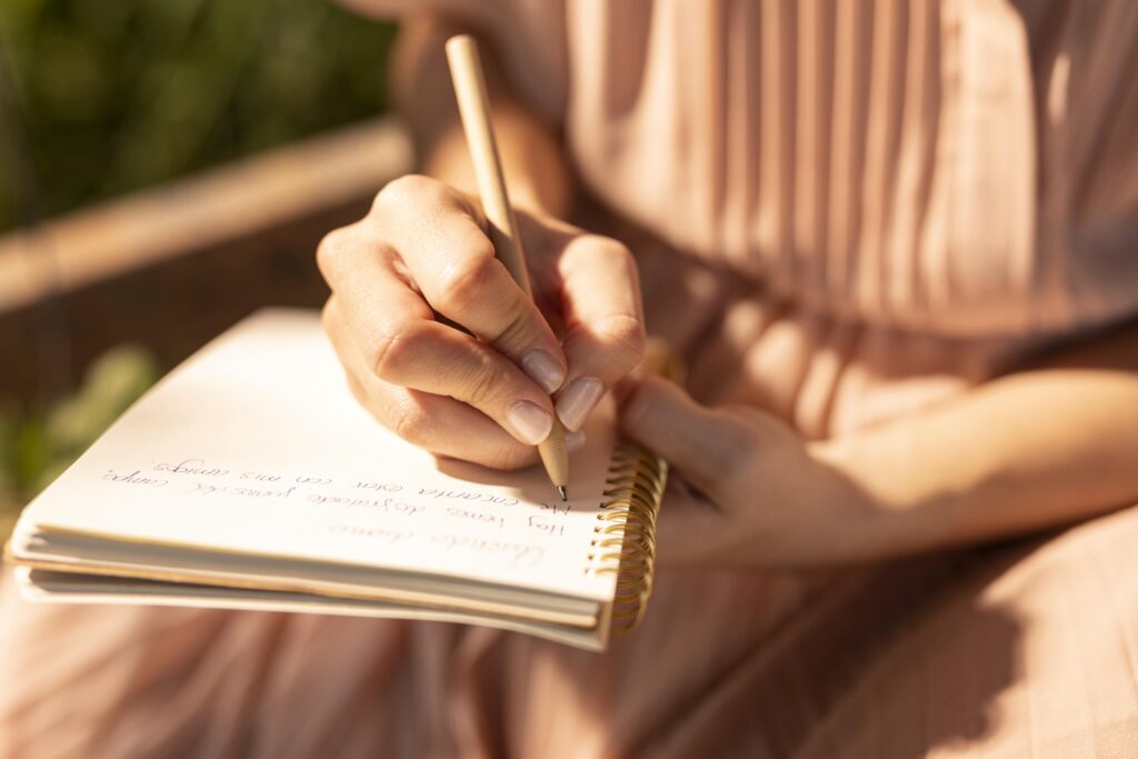 Imagem de uma mulher esboçando o roteiro para celebrante de casamento em um caderno. 